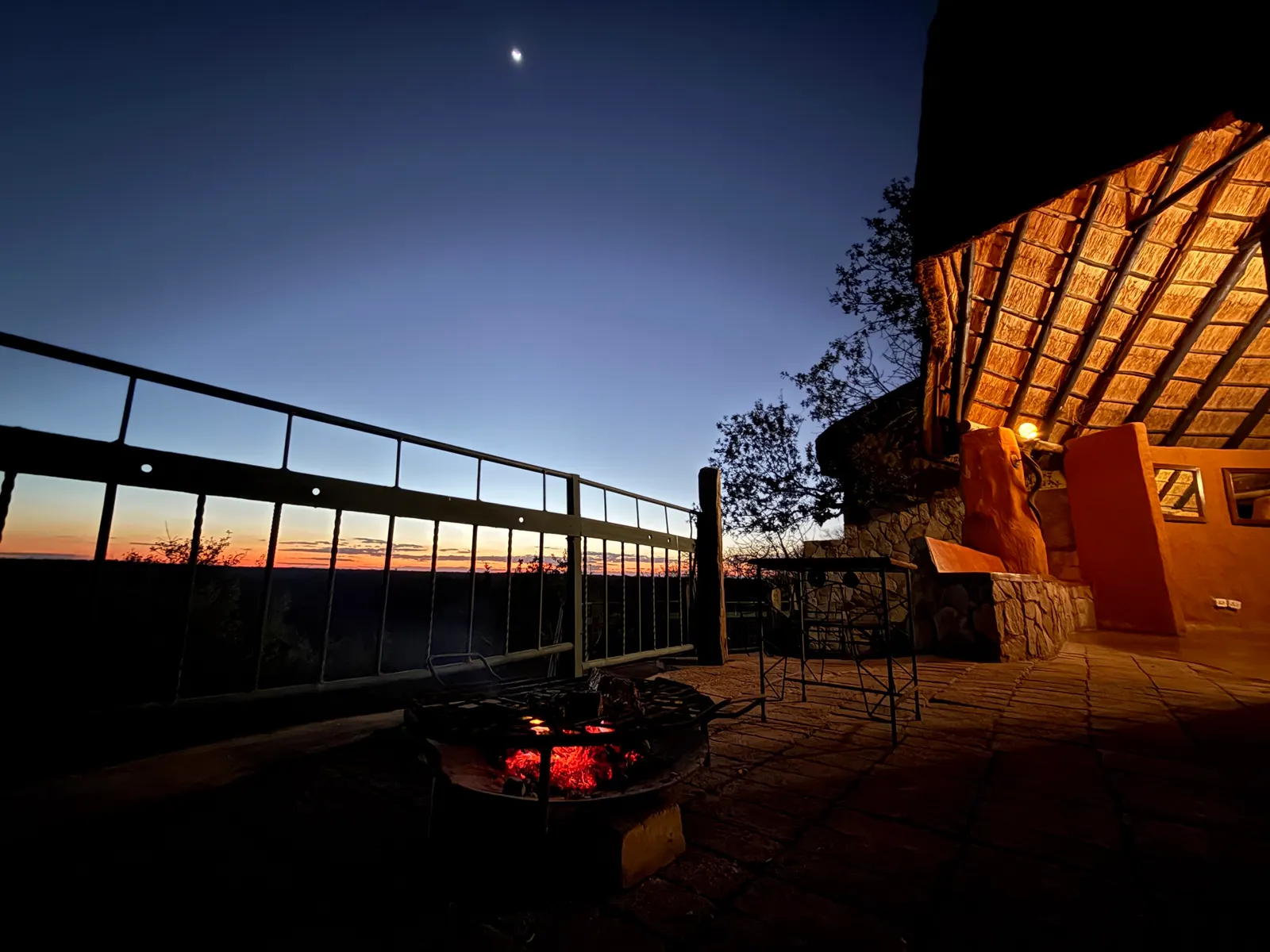 The boma fire at dusk at Khami Lodge, the first stars out above the thatch